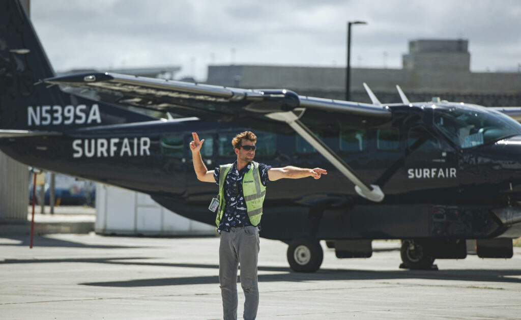 Ground crew signalling in front of a Surf Air Cessna Grand Caravan EX